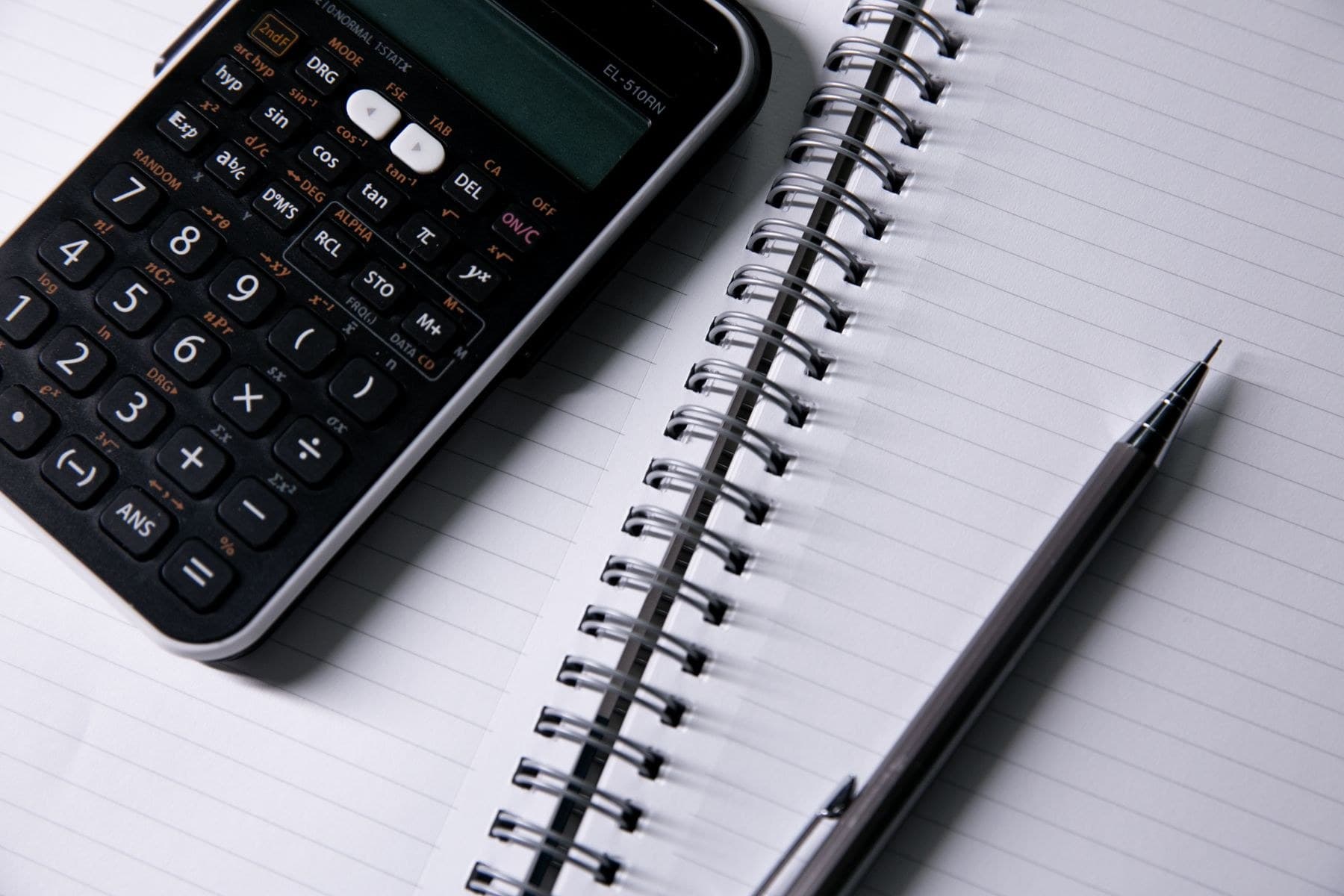 Calculator, open notebook and pen for comparing costs