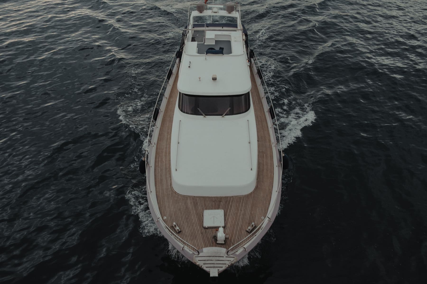 Overhead view of a white yacht moving through dark blue water
